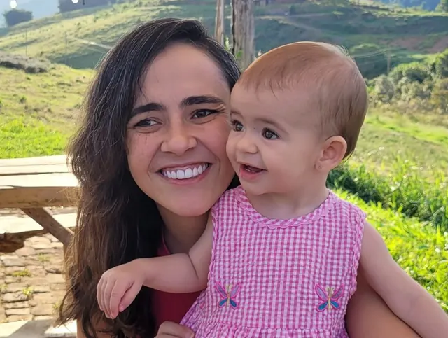 Aline Favaro com a filha, sorrindo ao ar livre