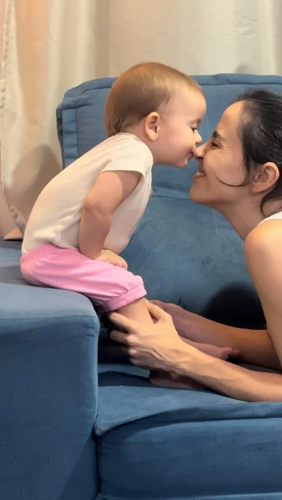Aline Favaro nariz com nariz com a filha no sofá
