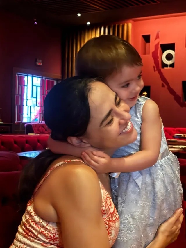 Aline Favaro abraçando a filha em um restaurante
